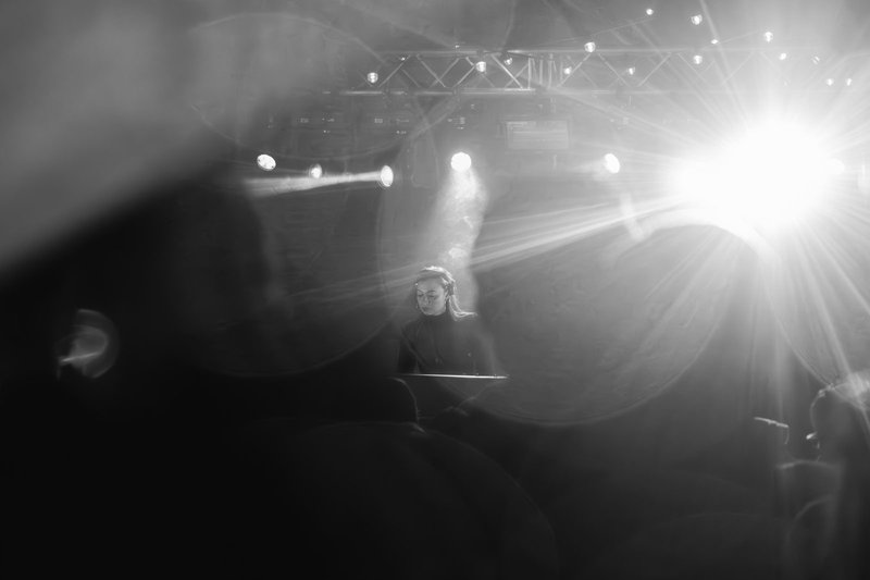 Demi in the spotlight with dramatic lens flare, festival stage
